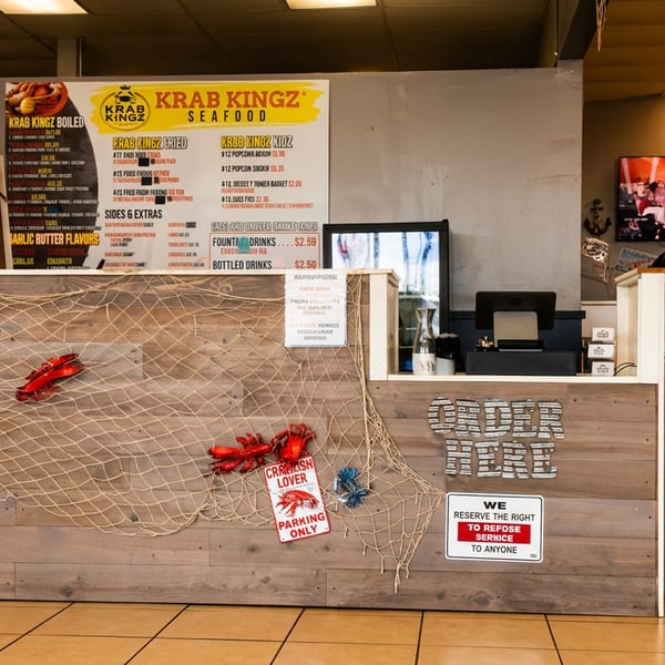 Krab Kingz Seafood counter decorated with fishing net, lobsters, menus, and an "Order Here" sign.