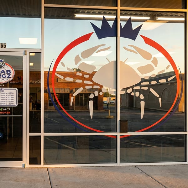Krab Kingz Seafood restaurant exterior with a large crab graphic and business hours displayed on the glass windows.