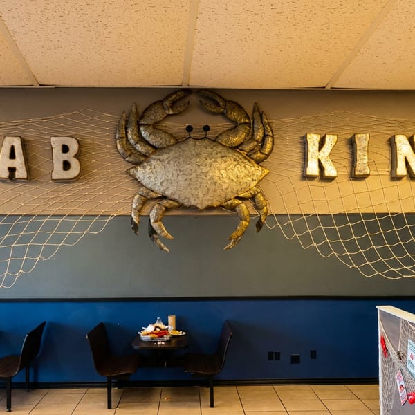 Krab Kingz restaurant interior with a large crab sign, fishing nets, and dining tables.